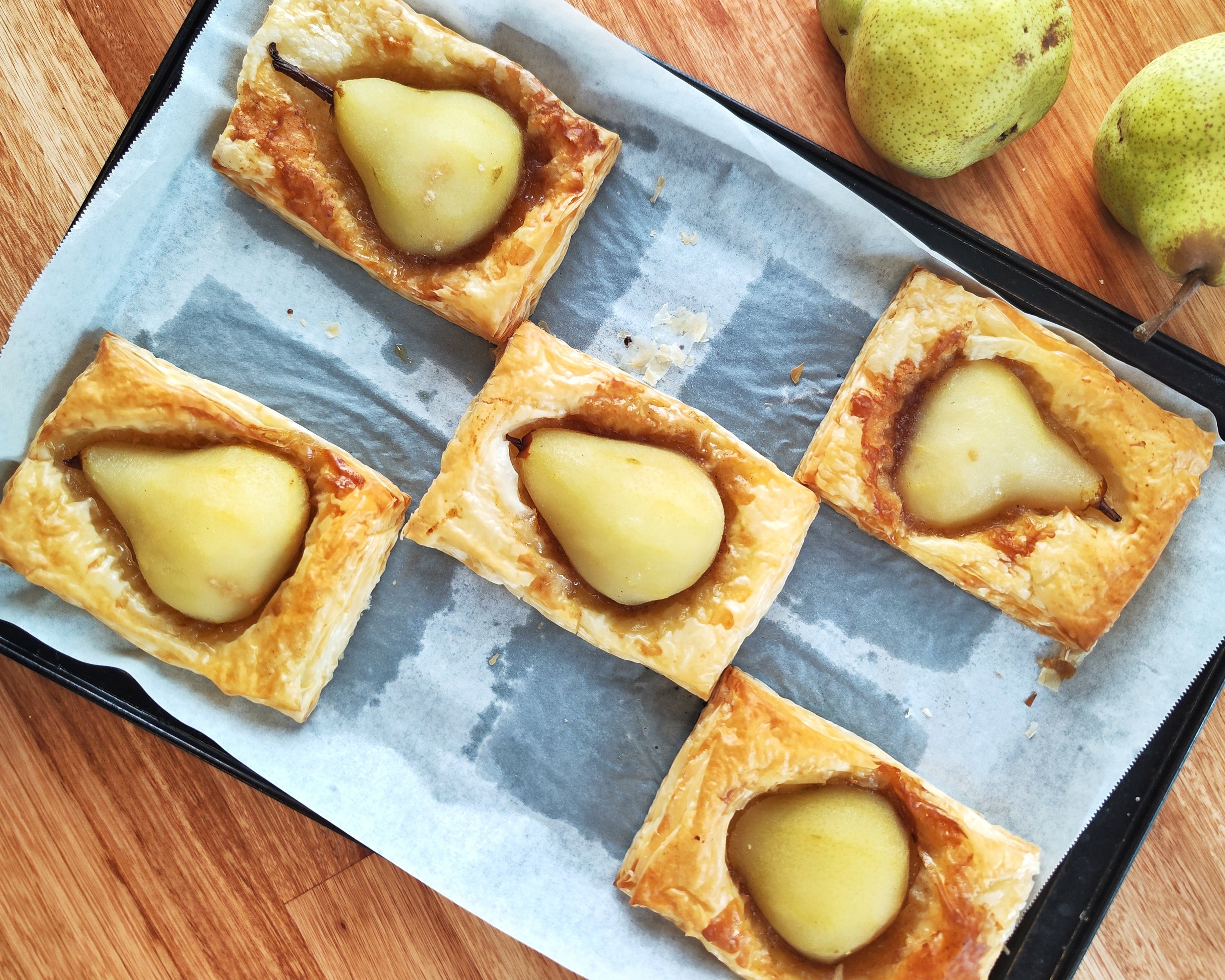 Poached pear halves wrapped in golden puff pastry with walnut filling
